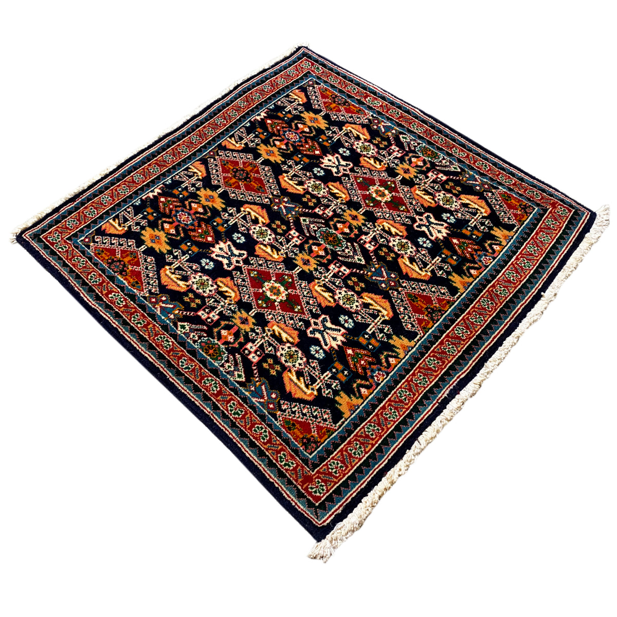 Rug 61x60 cm with diamond ornaments, dark blue-black, colored details, fringe at the corner.