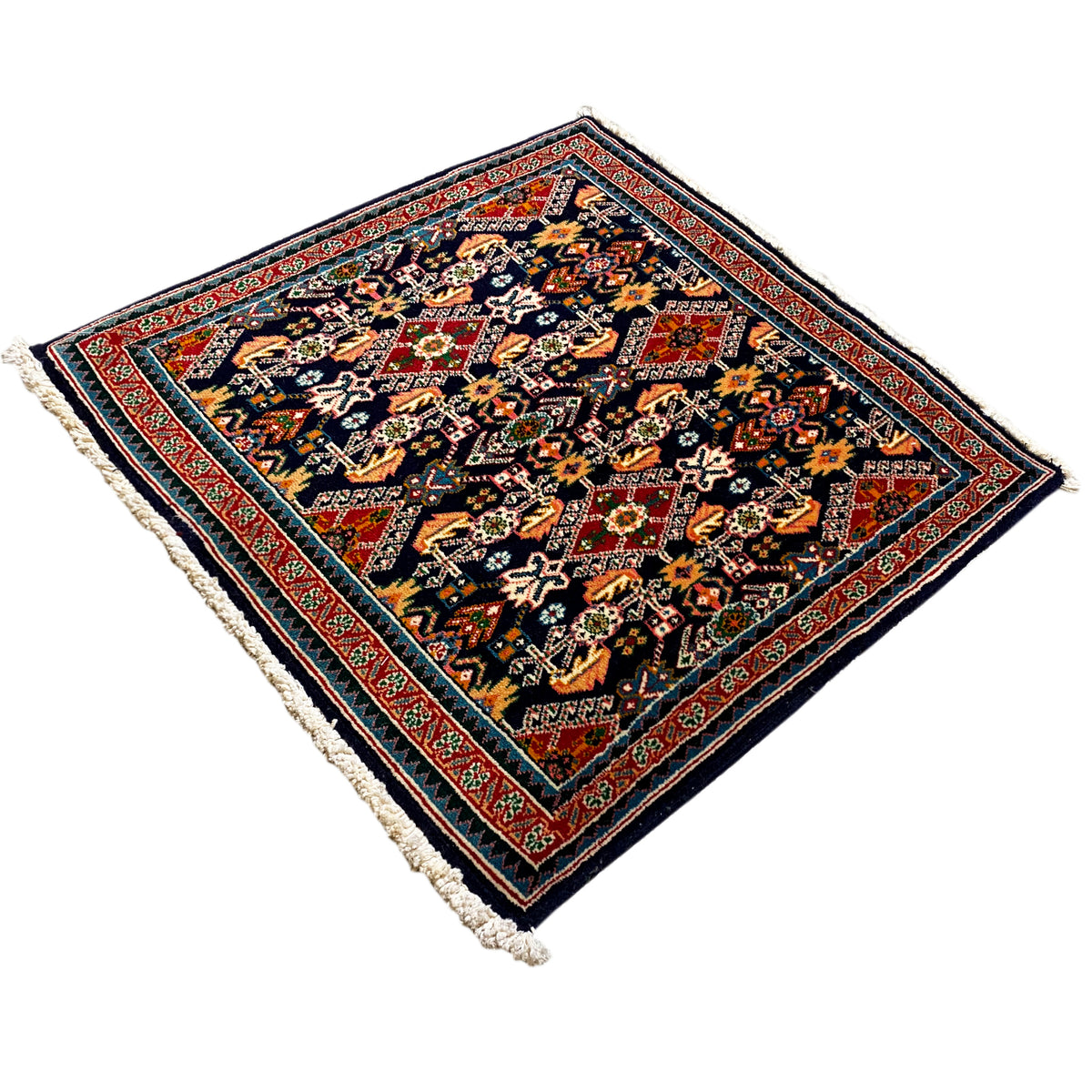Rug 61x60 cm in dark blue with red edging, colorful patterns, and white fringes.