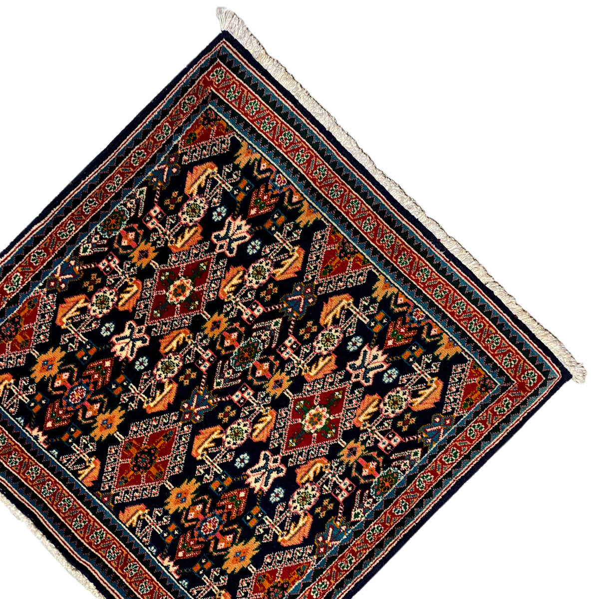 Rug 61x60 cm with corner fringes and a red border line, dark pattern in orange and green.
