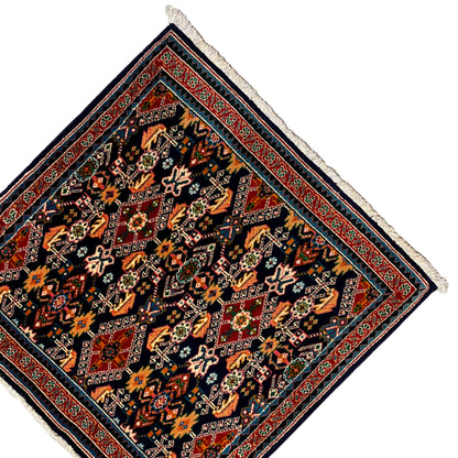 Rug 61x60 cm with corner fringes and a red border line, dark pattern in orange and green.