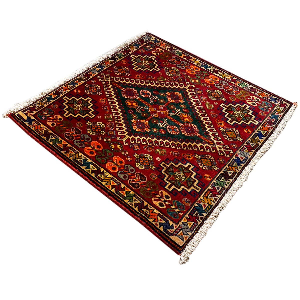 Corner view: burgundy carpet with multicolored ornaments and white fringes