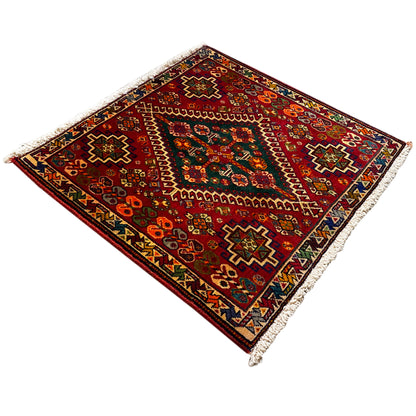 Corner view: burgundy carpet with multicolored ornaments and white fringes