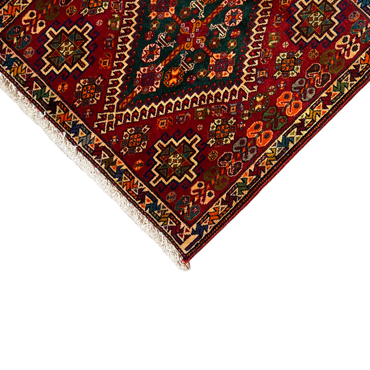 Close-up of a corner: burgundy ornamental pattern with colorful accents and fringe
