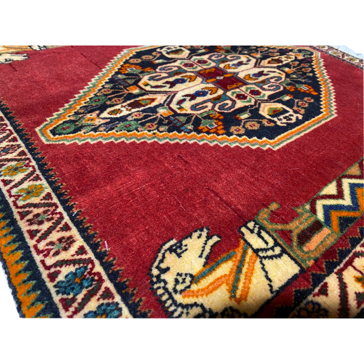 Close-up of the carpet surface: red fabric with a detailed medallion and colorful ornaments