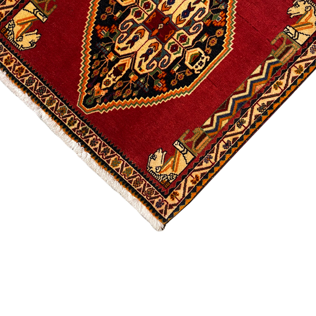 Corner view of the rug: red medallion, ornaments along the border, and white fringes