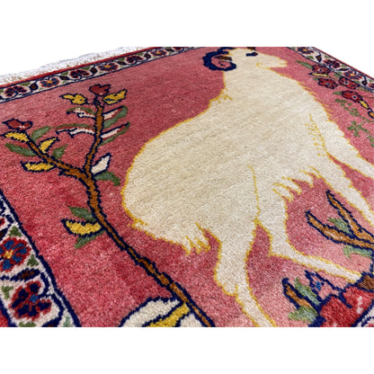 Close-up of a rug: red field with a light-colored animal motif, framed by floral designs and colorful details