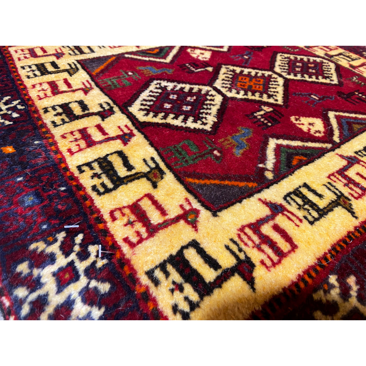 Close-up: carpet pattern with diamonds, ornaments, and vibrant accents on dark red