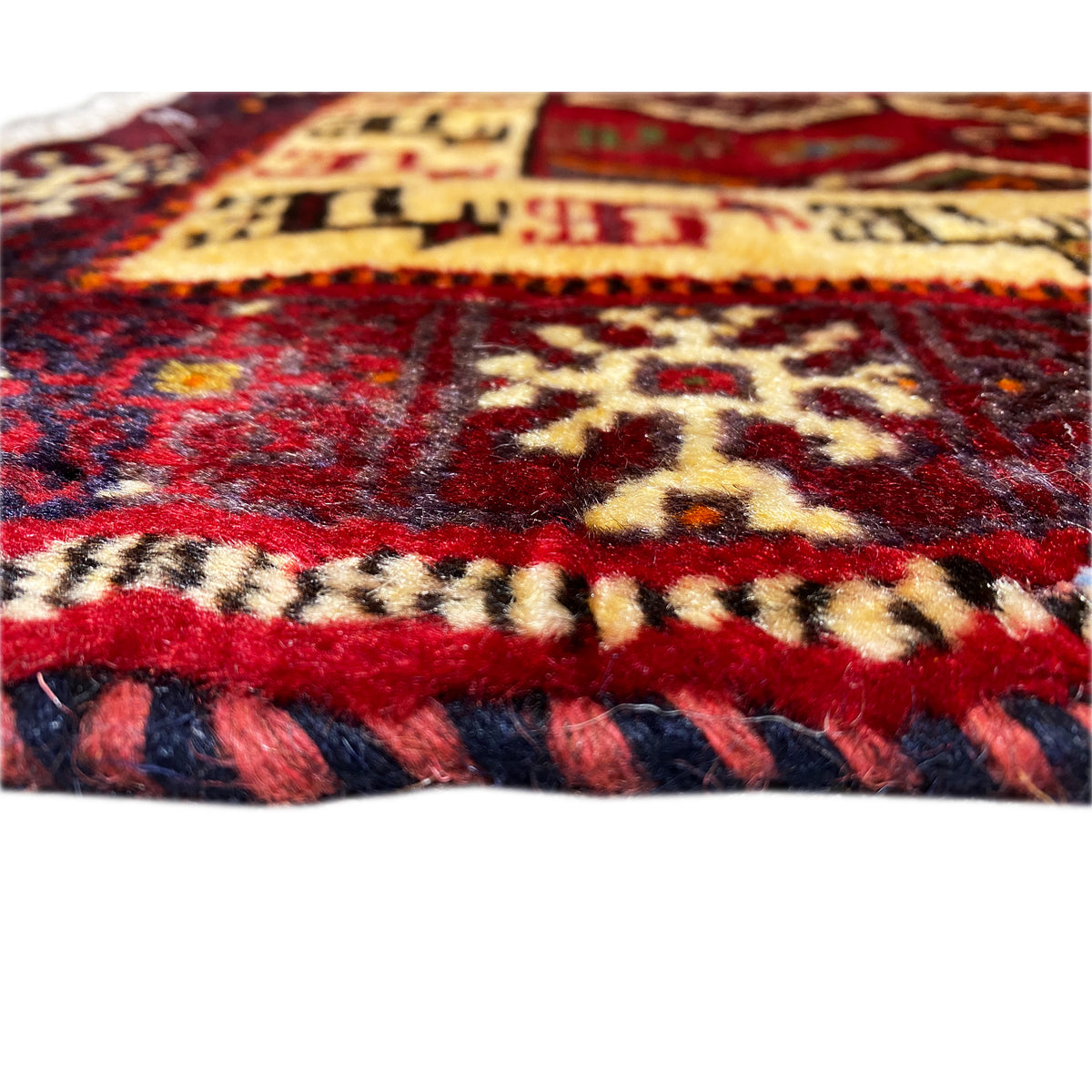 Detail of the carpet edge with fringe, dark red border and colorful ornaments