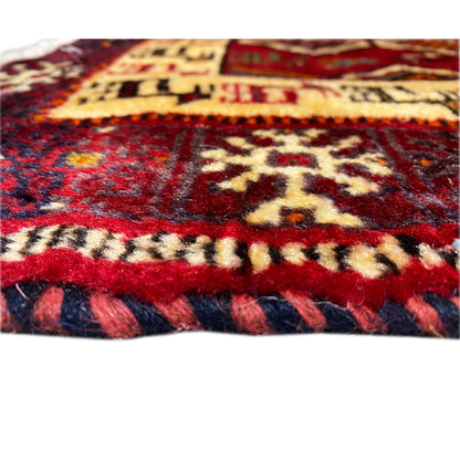 Detail of the carpet edge with fringe, dark red border and colorful ornaments
