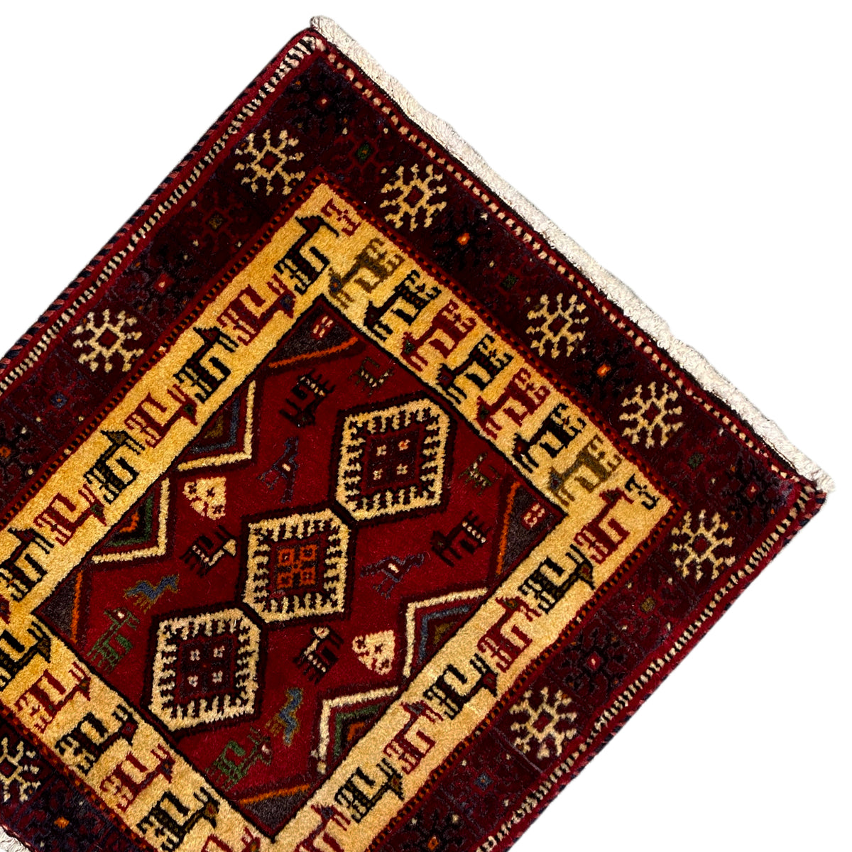 Carpet corner with a beige border, dark red background, and geometric diamonds in the center