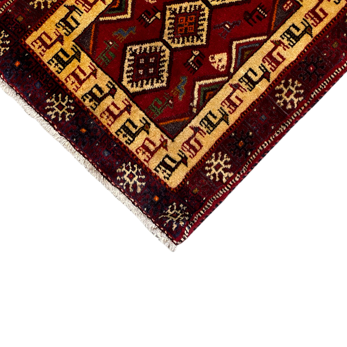 Close-up of the carpet edge: dark red with a beige patterned border and fringe