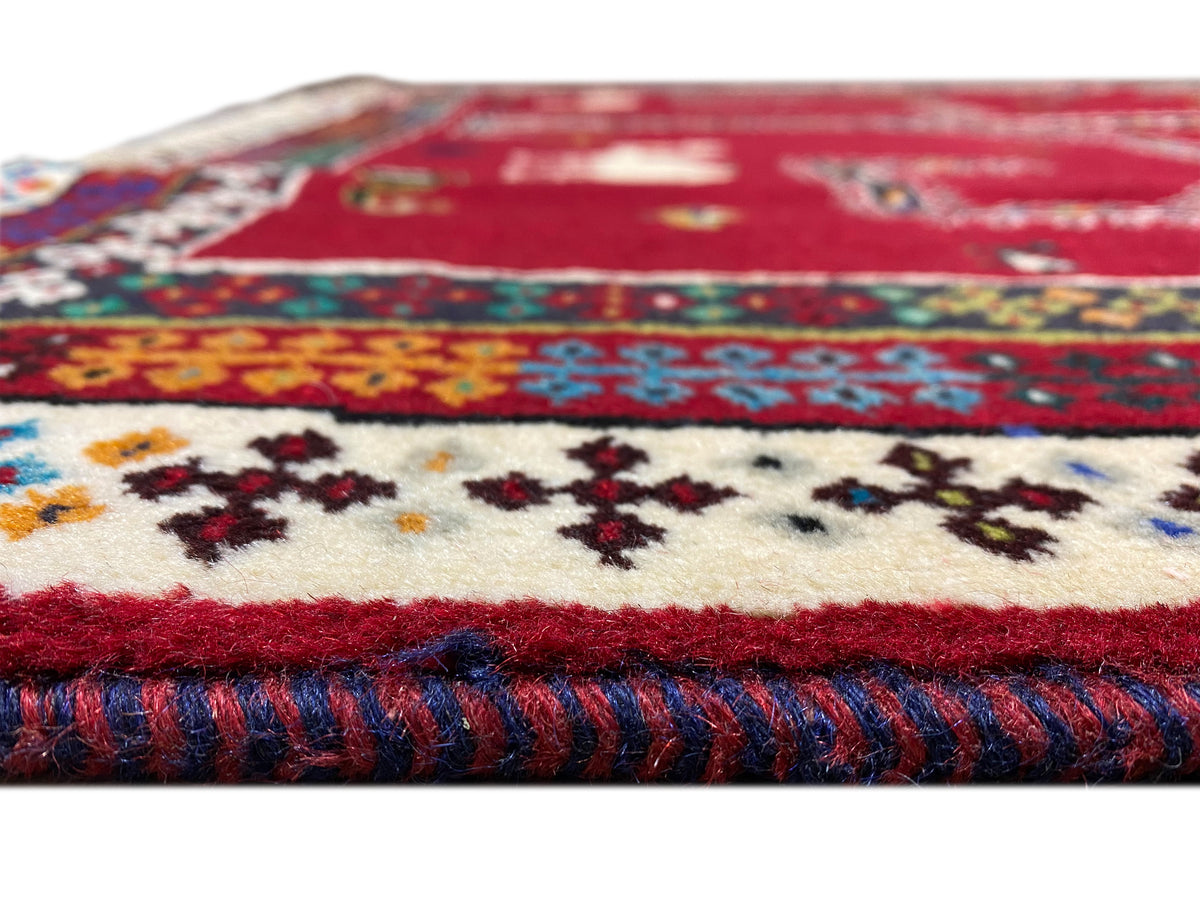 Nahaufnahme: Teppichkante und Flor, rotes Gewebe mit farbigen Stickereimotiven