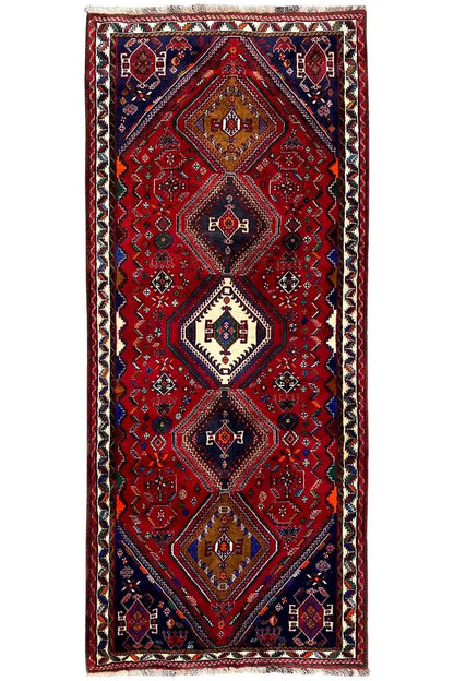 Rectangular Oriental rug runner: red central pattern with blue medallions, framed border edge