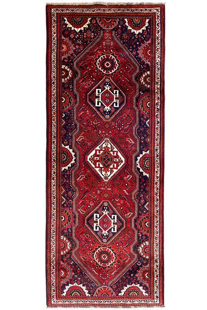 Oriental rug runner (297x115 cm) with a red ground, central diamonds, and dark blue borders