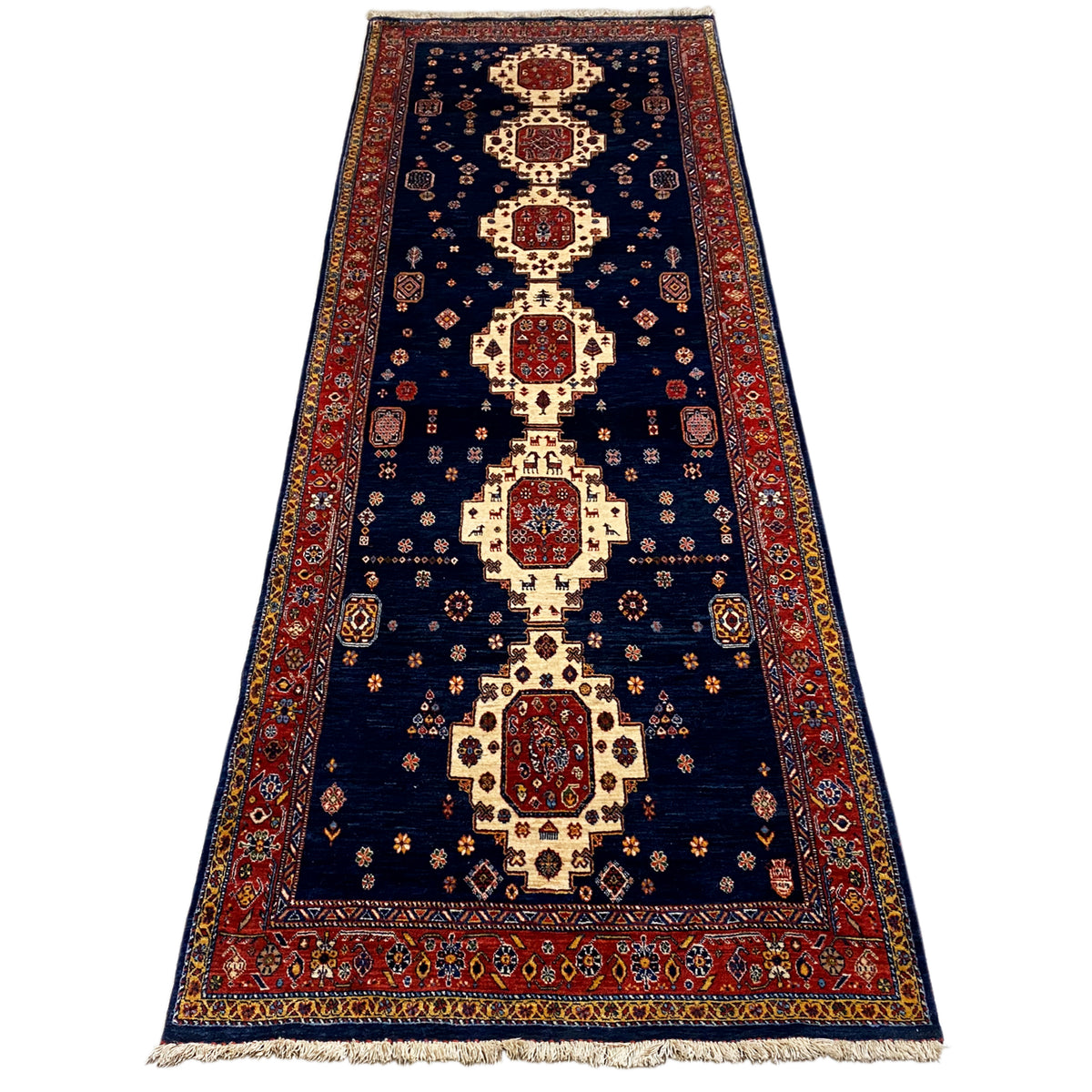Dark blue runner rug with a red border, central medallion, and fringes