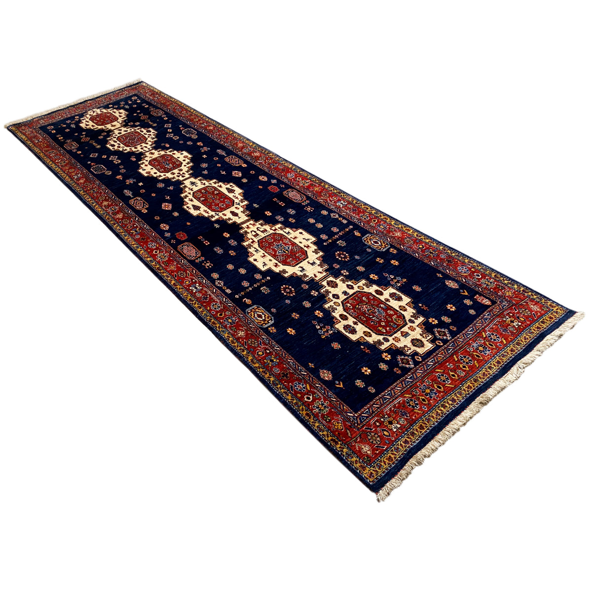 Dark blue runner rug in an oblique view with red borders and medallions