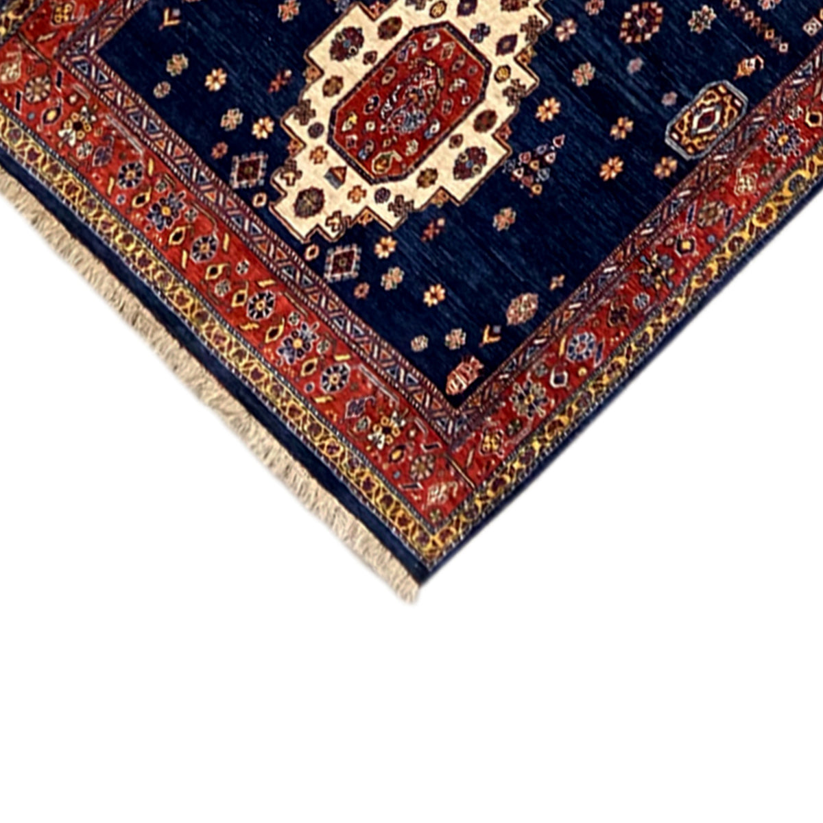 Corner view: dark blue rug with a cream-and-red medallion and short fringes
