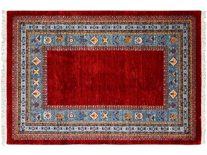 Roter Teppich mit blauem Rahmen und mehrfarbigen Ornamenten, flach liegend.