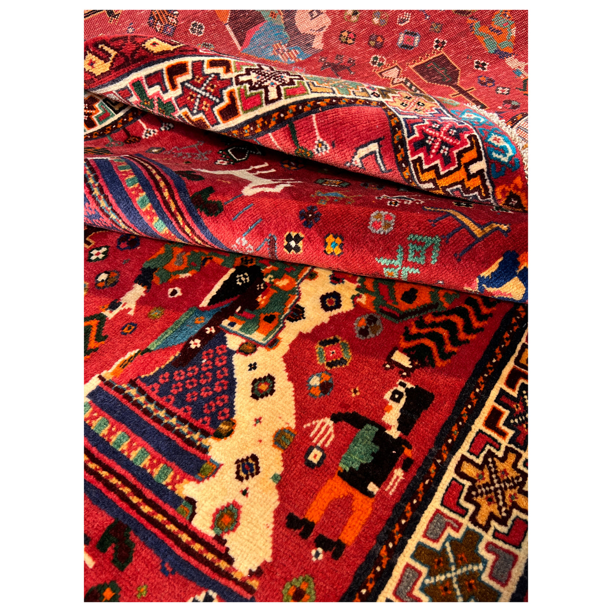 Qashqai rug close-up: red field with figures, border pattern, and pile