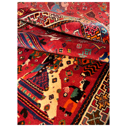 Qashqai rug close-up: red field with figures, border pattern, and pile