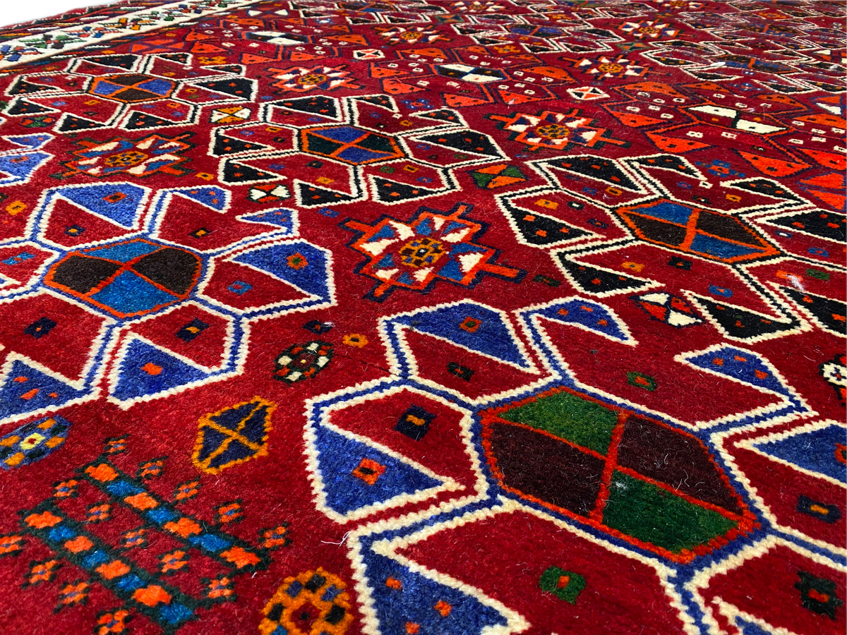 Detailaufnahme der Oberfläche: rotes Muster aus Rauten und Sternen in Blau, Grün und Beige