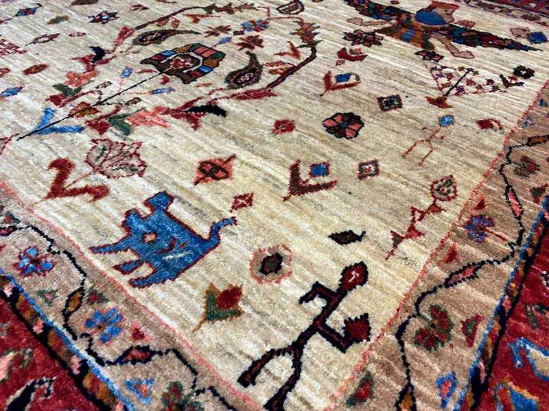 Close-up: beige pile with a dense pattern of small figures and colorful ornaments.