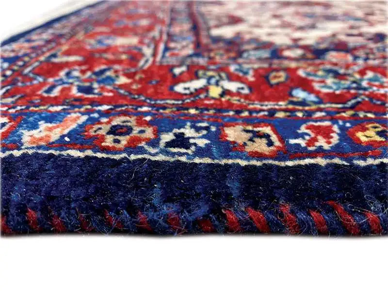 Carpet detail: blue-red woven ornamental pattern with beige accents, dense pile