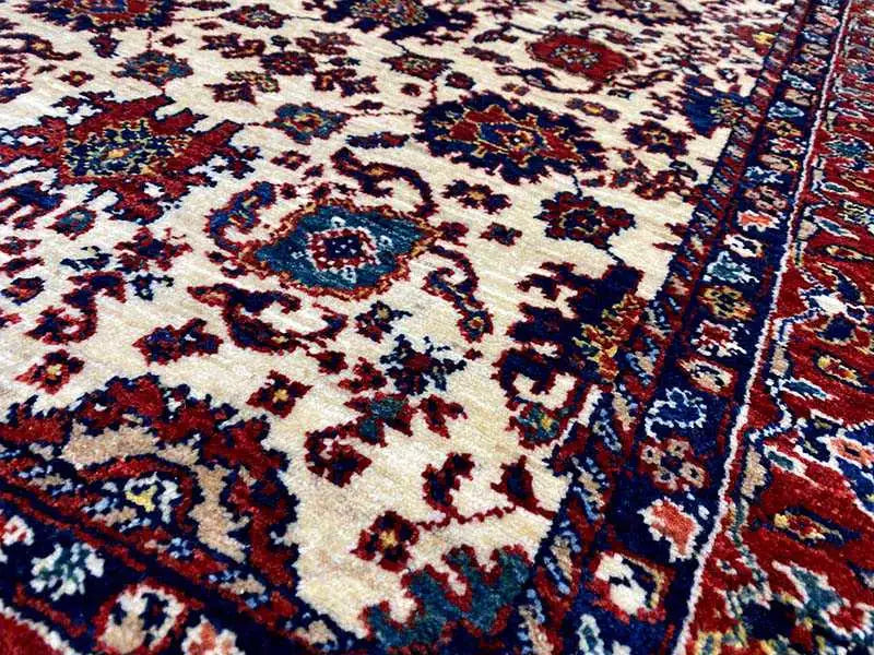 Carpet detail with a delicate vine and medallion pattern in cream, blue, and red