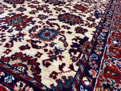 Carpet detail with a delicate vine and medallion pattern in cream, blue, and red