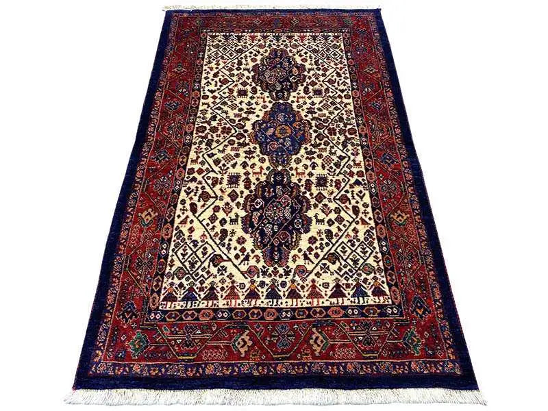 Qashqai rug with a cream-colored central medallion, dark blue border, and red pattern