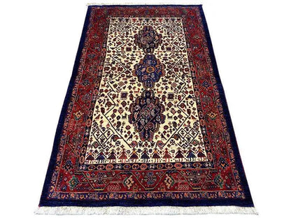 Qashqai rug with a cream-colored central medallion, dark blue border, and red pattern