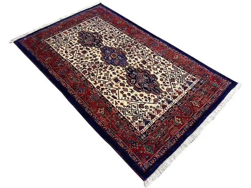 Qashqai rug, diagonal view: red border, cream-colored background with medallions
