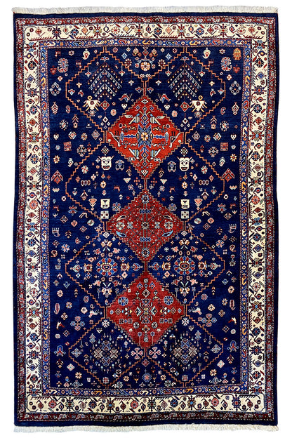 Blue Oriental rug with a red medallion and ornamental border, with fringes.