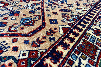 Area rug with a beige background, blue and red ornaments, and border lines