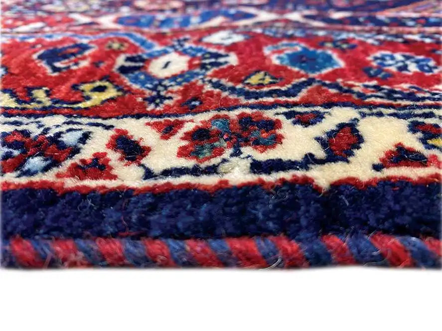 Close-up of a rug edge with colorful ornaments and a fluffy pile
