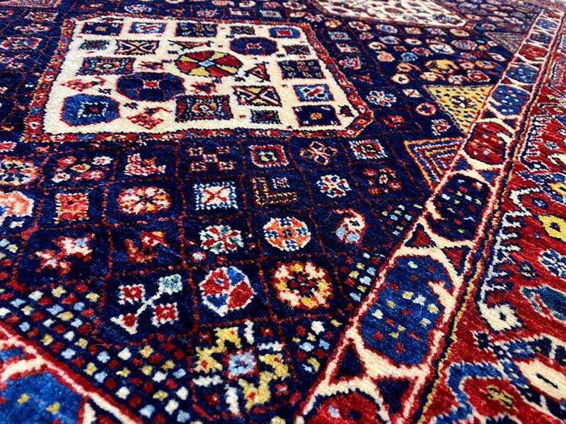 Close-up of a carpet pattern with dark blue, red, and cream-colored squares