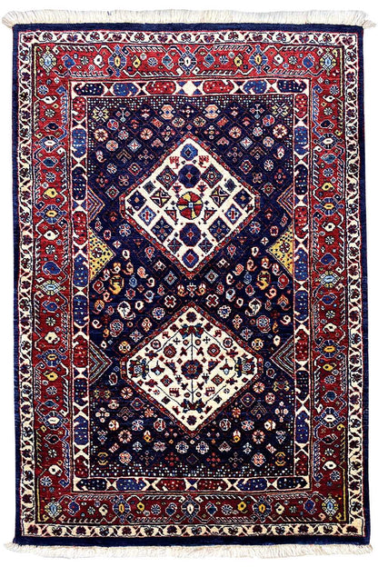 Rug with dark blue, red border, central diamond pattern, and fringes