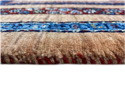Close-up of a carpet edge with fringes, beige surface and blue patterned stripe