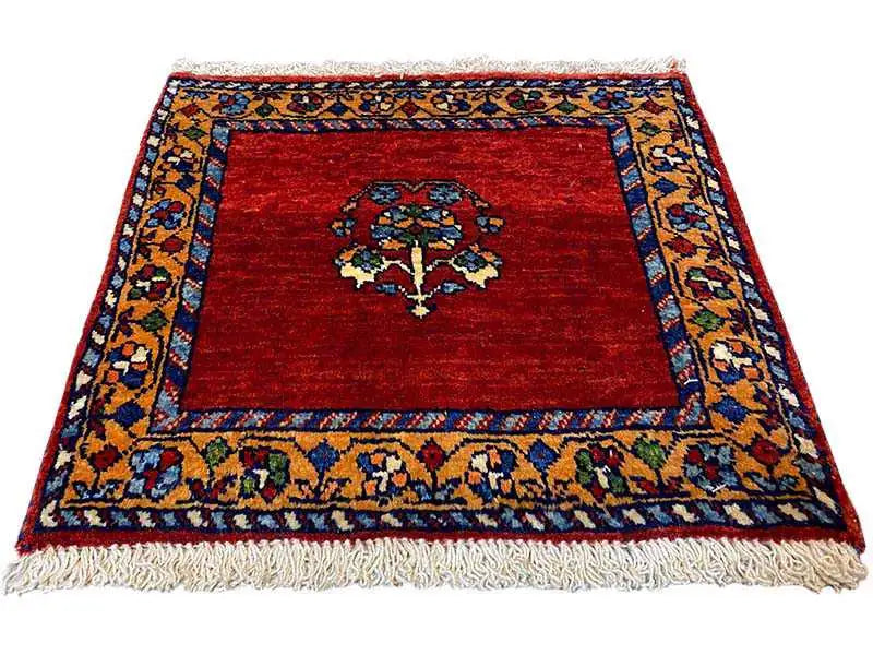 Square red rug with a blue-and-gold border, central medallion, and fringe
