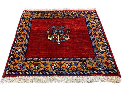 Square red rug with a blue-and-gold border, central medallion, and fringe