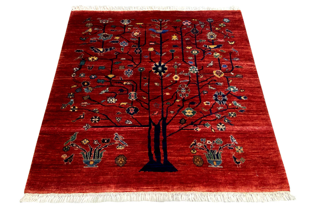 Reddish-brown rug with a central tree motif, ornamented, with fringes along the edge