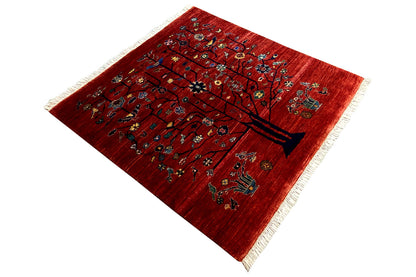 Triangular-looking view of a red carpet with a tree motif and colorful ornaments