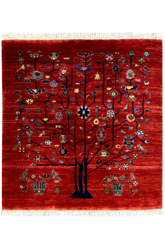 Reddish-brown rug with a tree motif and floral ornament, with fringes along the edge