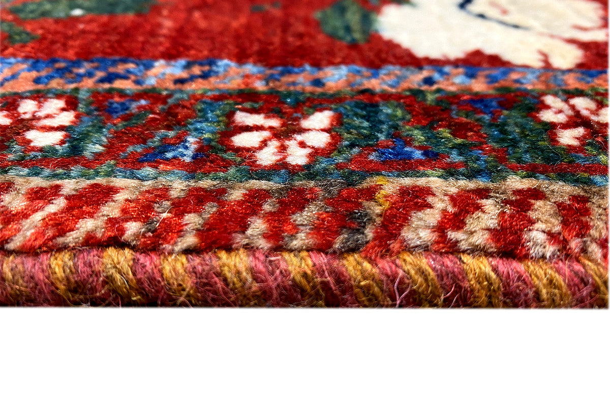 Rug with fringed edging, multicolored floral and striped patterns on a red background