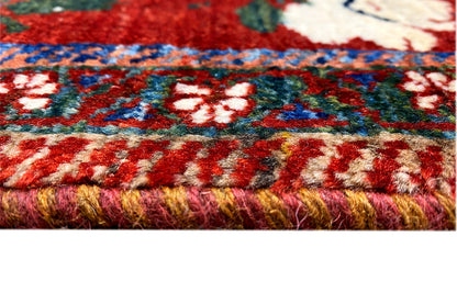 Rug with fringed edging, multicolored floral and striped patterns on a red background