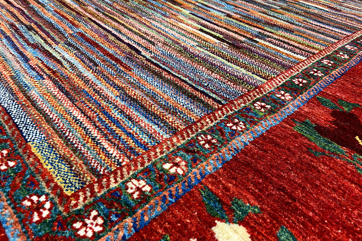 Close-up: multicolored striped carpet pattern with a red border area and flowers