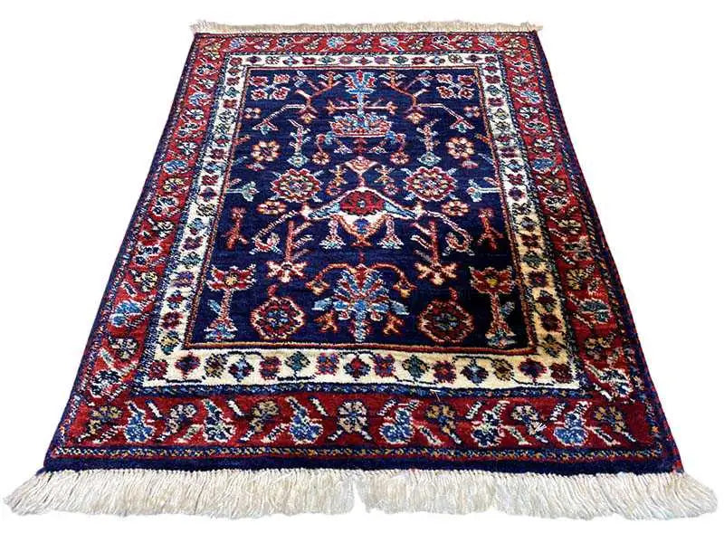 Rug with a blue central motif, red decorative borders, a white edge, and fringes