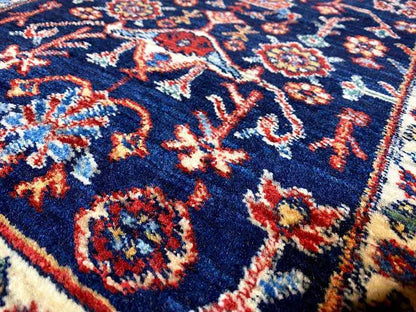 Close-up of carpet pile: dark blue pattern with red, green, and beige ornaments