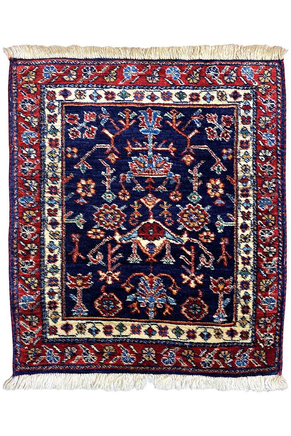 Square rug with a blue central medallion, red border ornaments, and fringes
