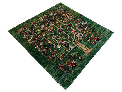 Green Oriental rug with a tree motif and colorful ornaments, photographed diagonally
